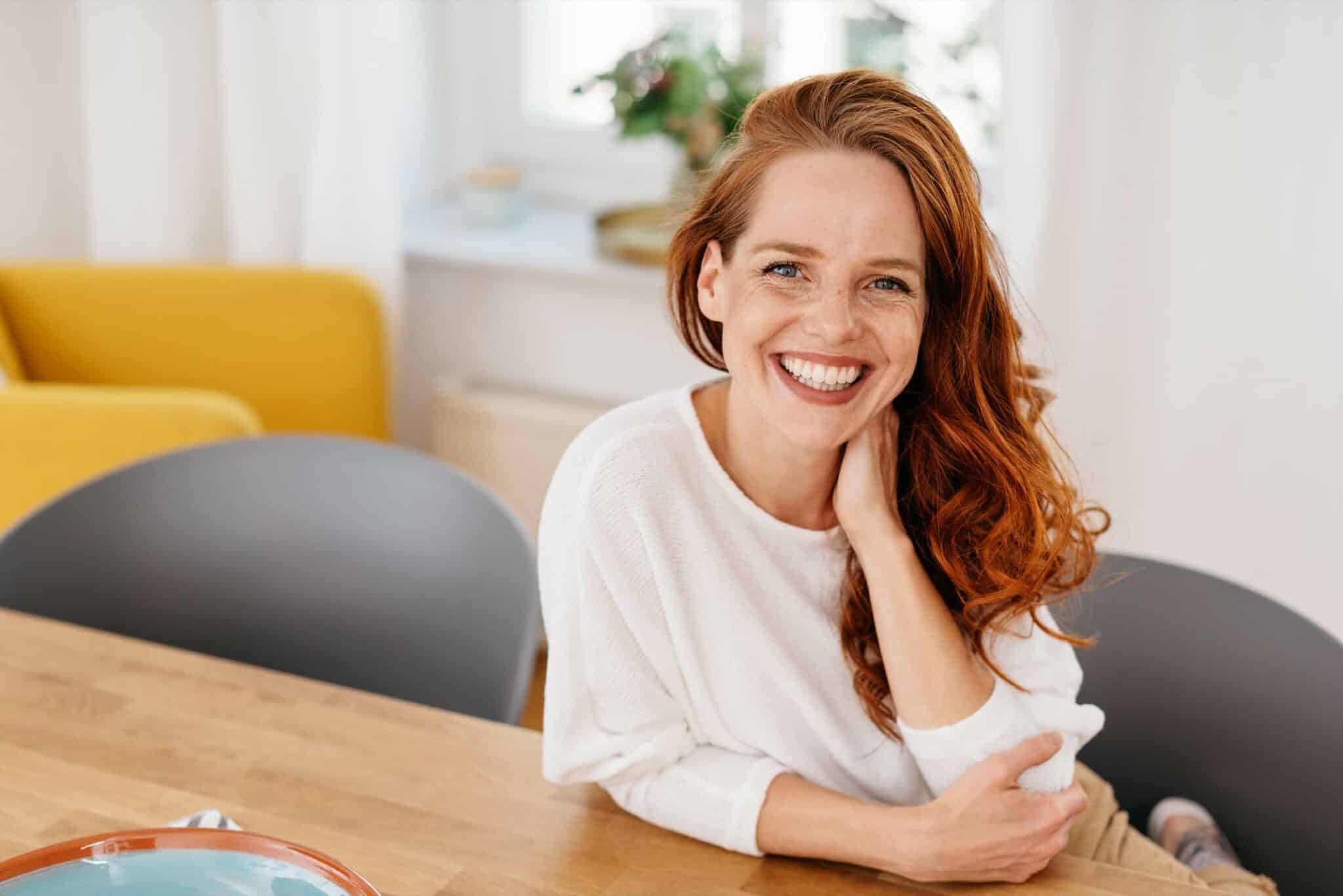 Happy relaxed young woman sitting at a table